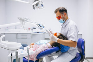 Hombre dentista atendiendo a una mujer paciente en su consultorio
